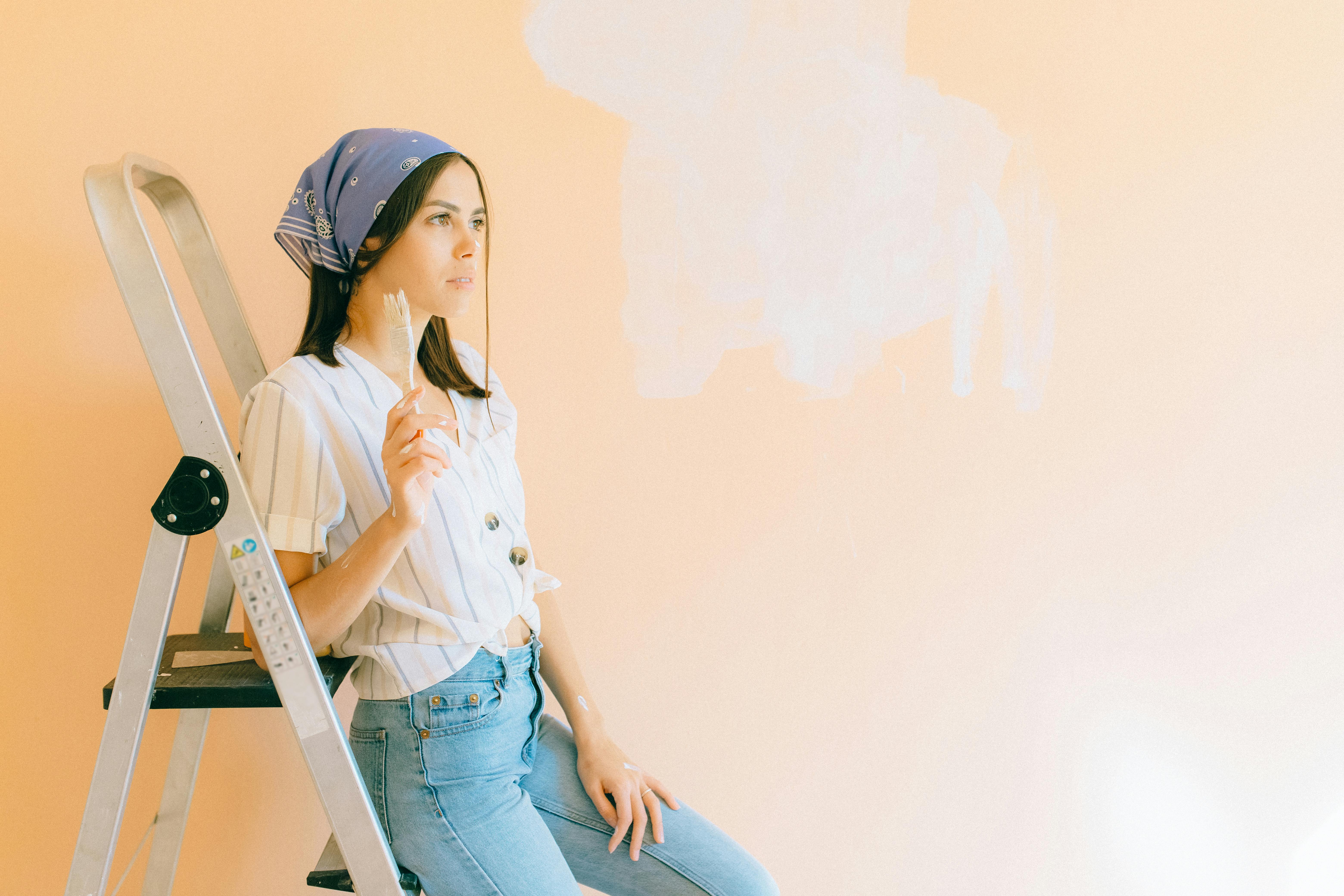 A woman painting a wall in light hues indoors